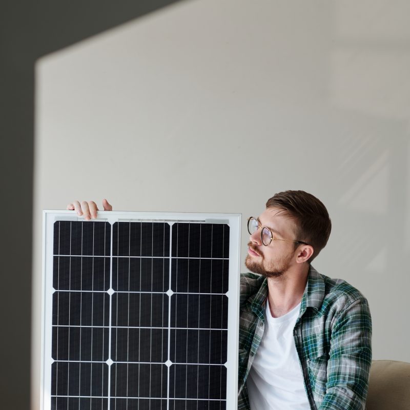 Excited young man in plaid shirt looking at solar panel